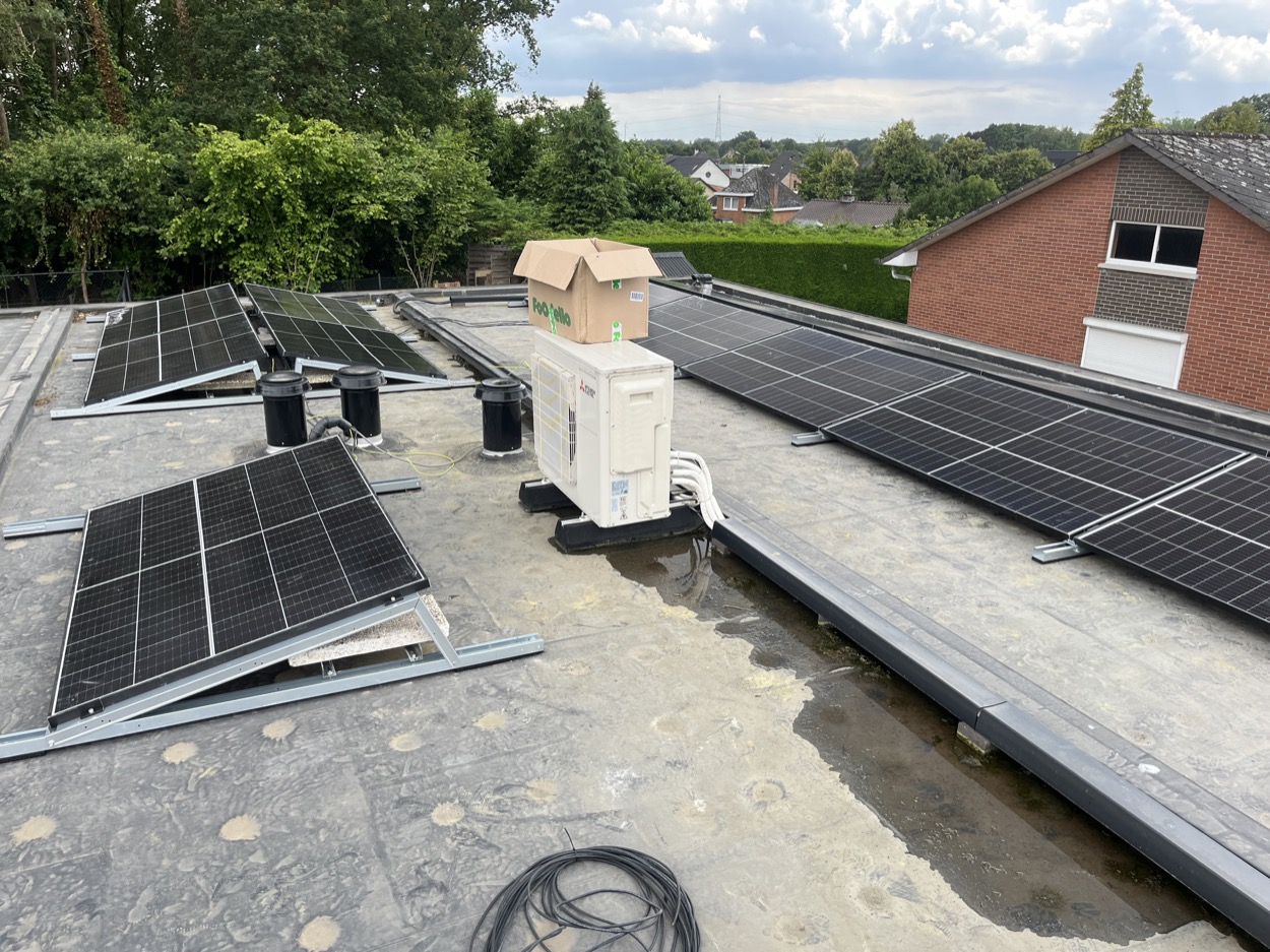 Zonnepanelen en buitenunit airco op plat dak.